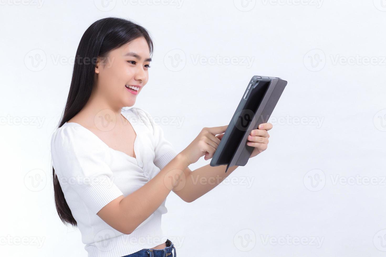 imagen de hermosos estudiantes universitarios asiáticos están usando un teléfono de tableta con placer en un fondo blanco foto