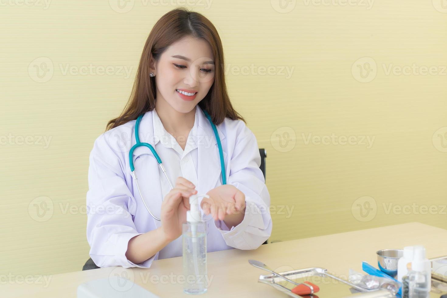 A woman doctor in white lab coat sit and pump the alcohol gel to clean her hands photo