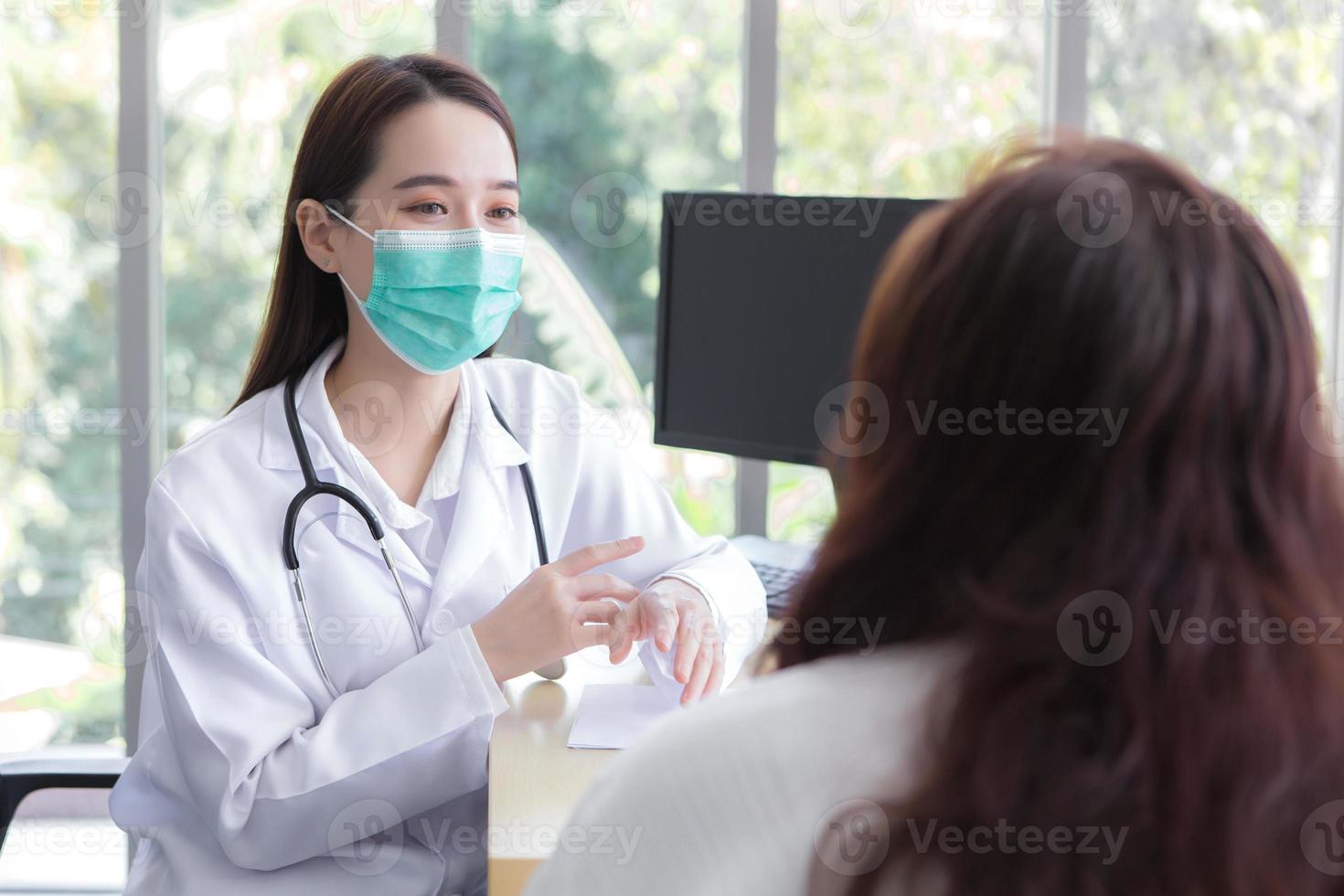 Una doctora revisa la salud de una anciana asiática mientras ambas usan mascarilla médica en una sala de examen en un hospital. foto