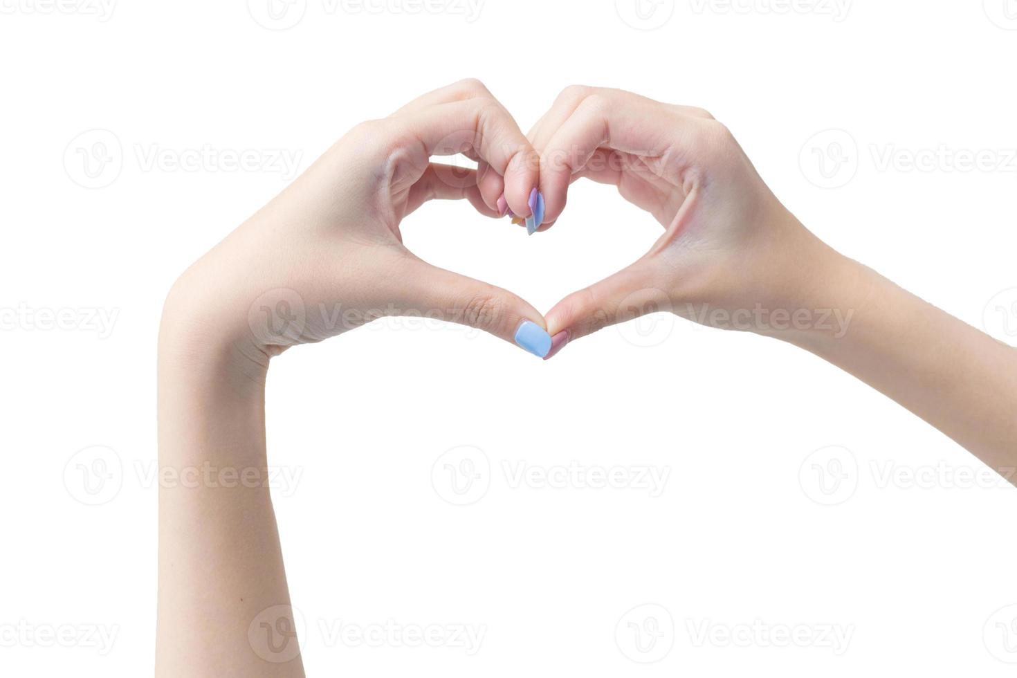 hermosa mano femenina muestra el símbolo del corazón como signo de amor en un fondo blanco en el concepto de manicura. foto