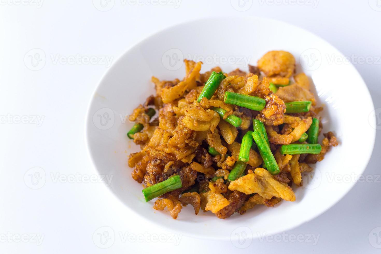 Stir fried crispy pork and yardlong bean with Thai spicy curry paste on white plate in Thai food style. photo