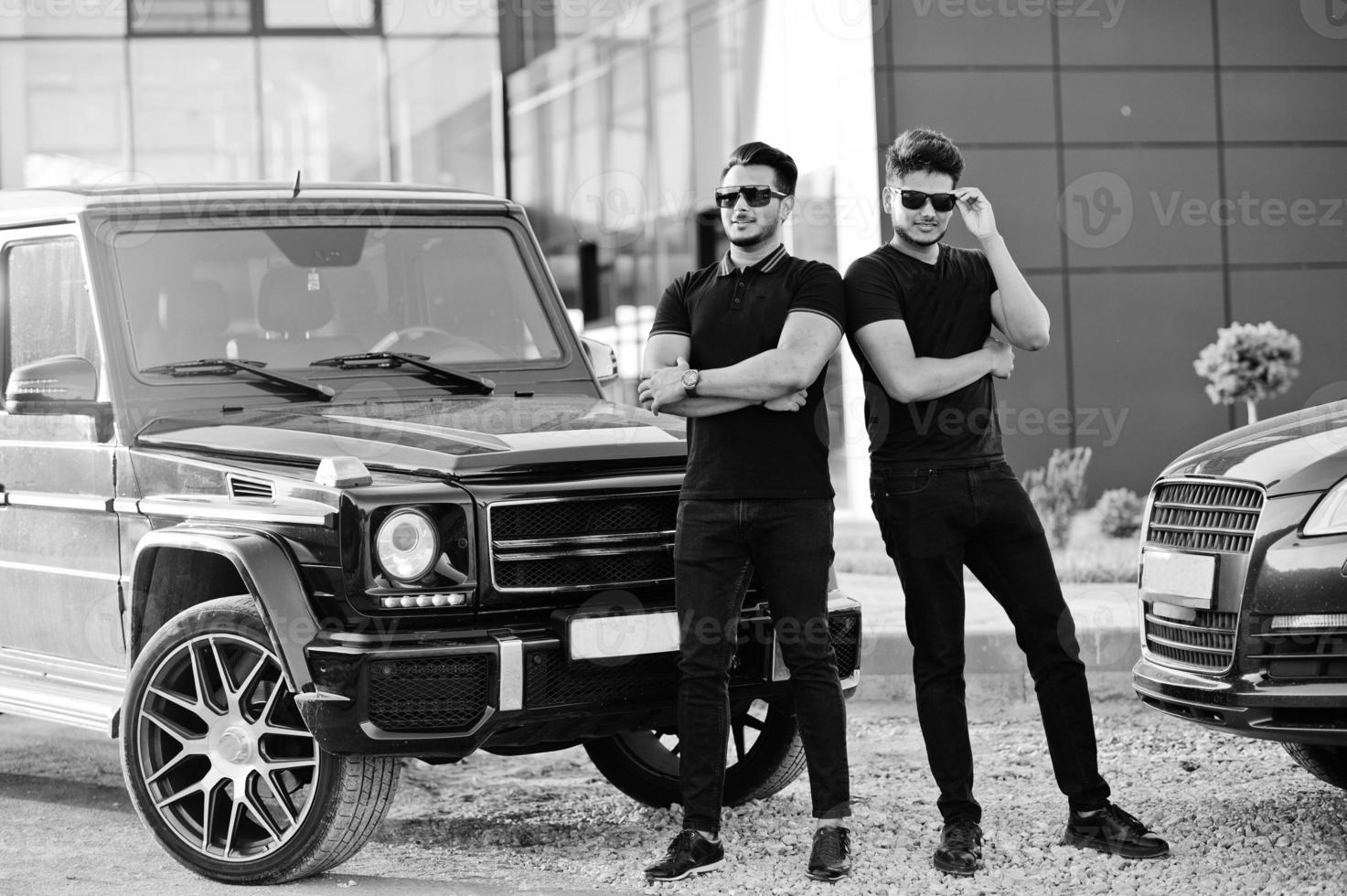 Two asian brothers man wear on all black posed near suv cars. photo