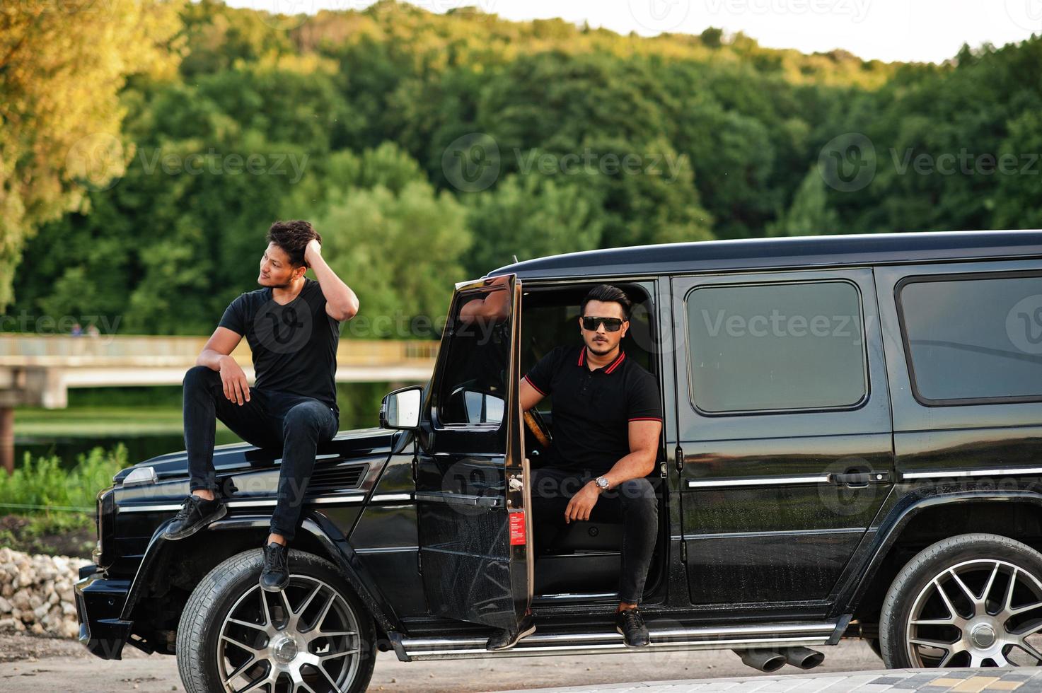 Two asian brothers man wear on all black posed near suv car. photo