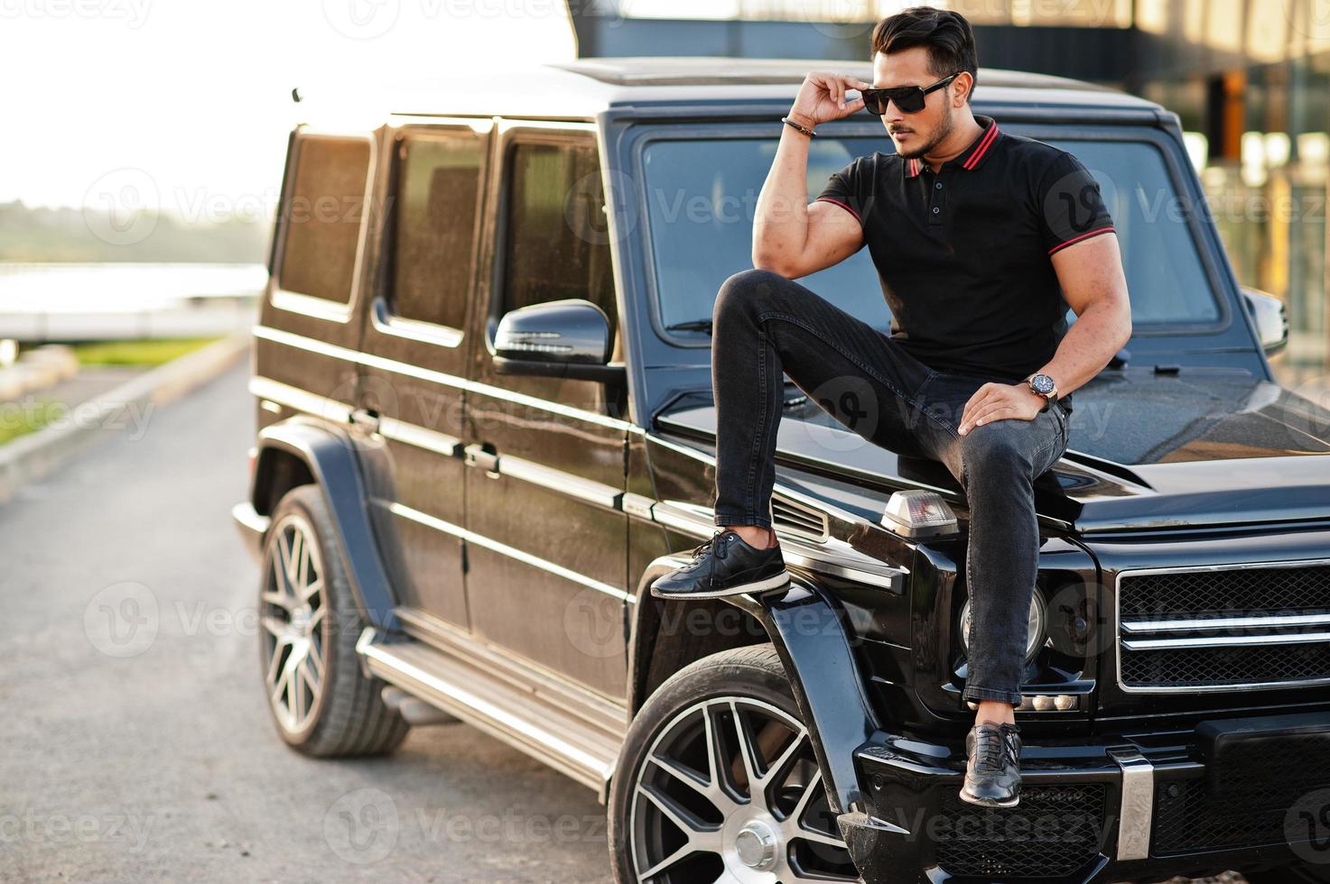 Asian man wear on all black posed near suv car. photo