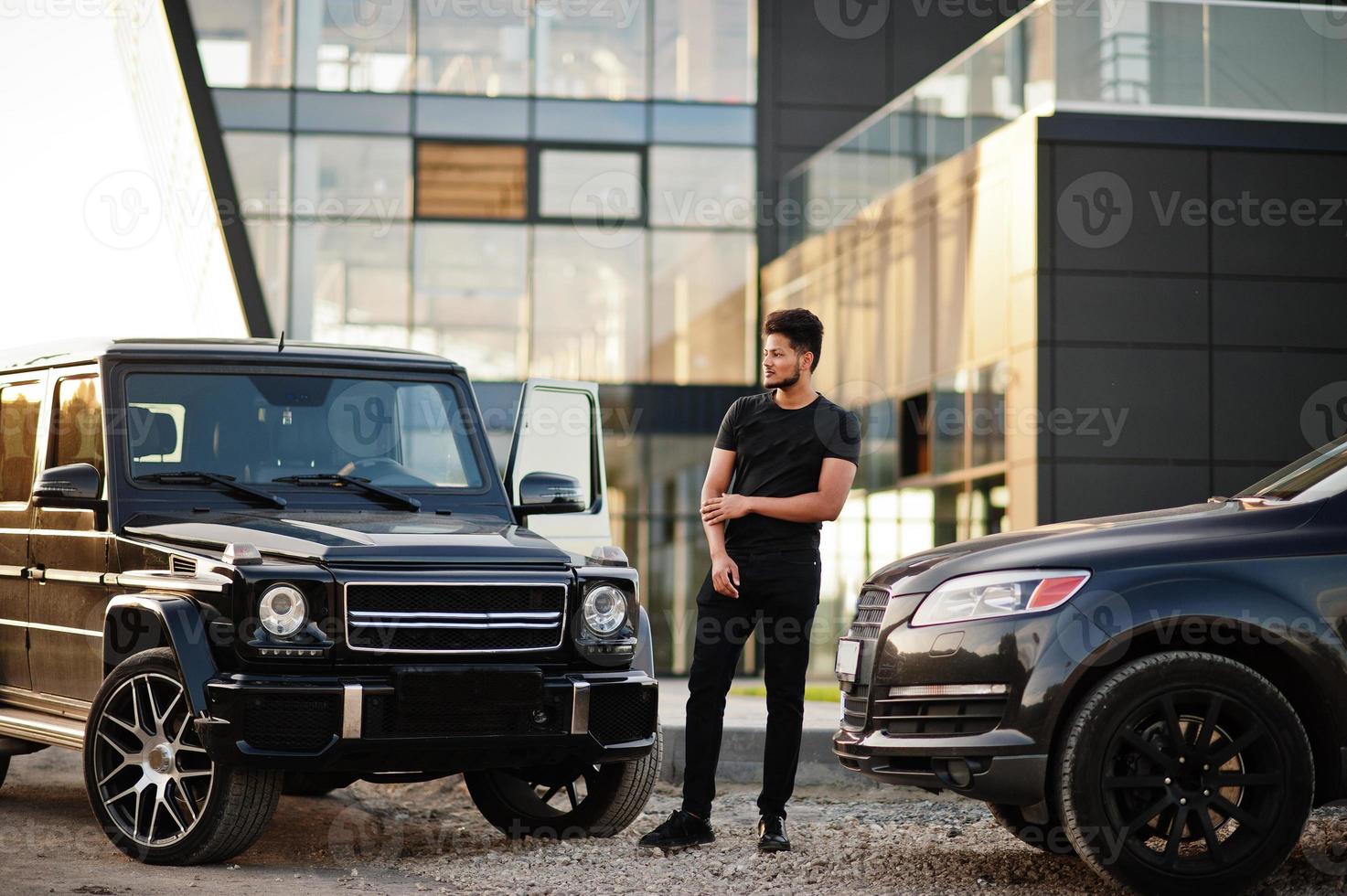Asian man wear on all black posed near suv car. photo