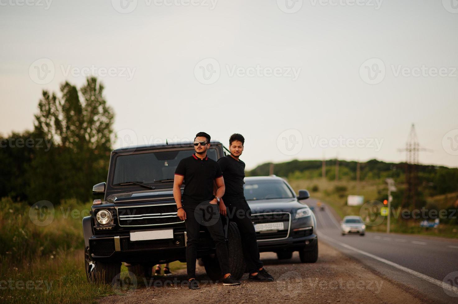 Two asian brothers man wear on all black posed near suv cars. photo