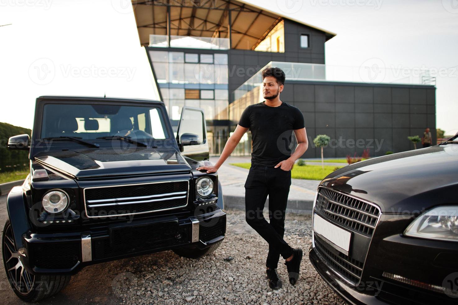 Asian man wear on all black posed near suv car. photo