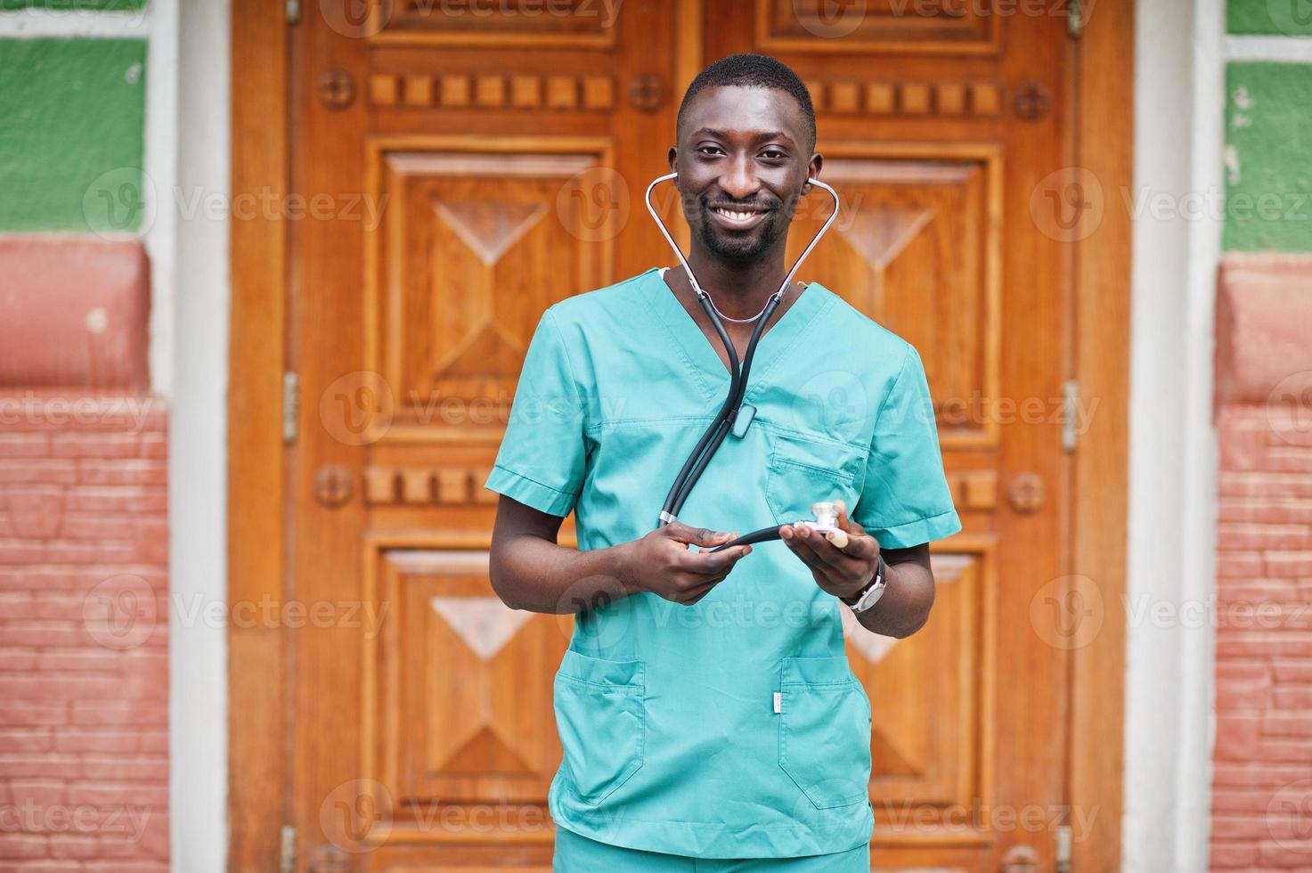 Portrait of African male doctor with stethoscope wearing green coat. photo