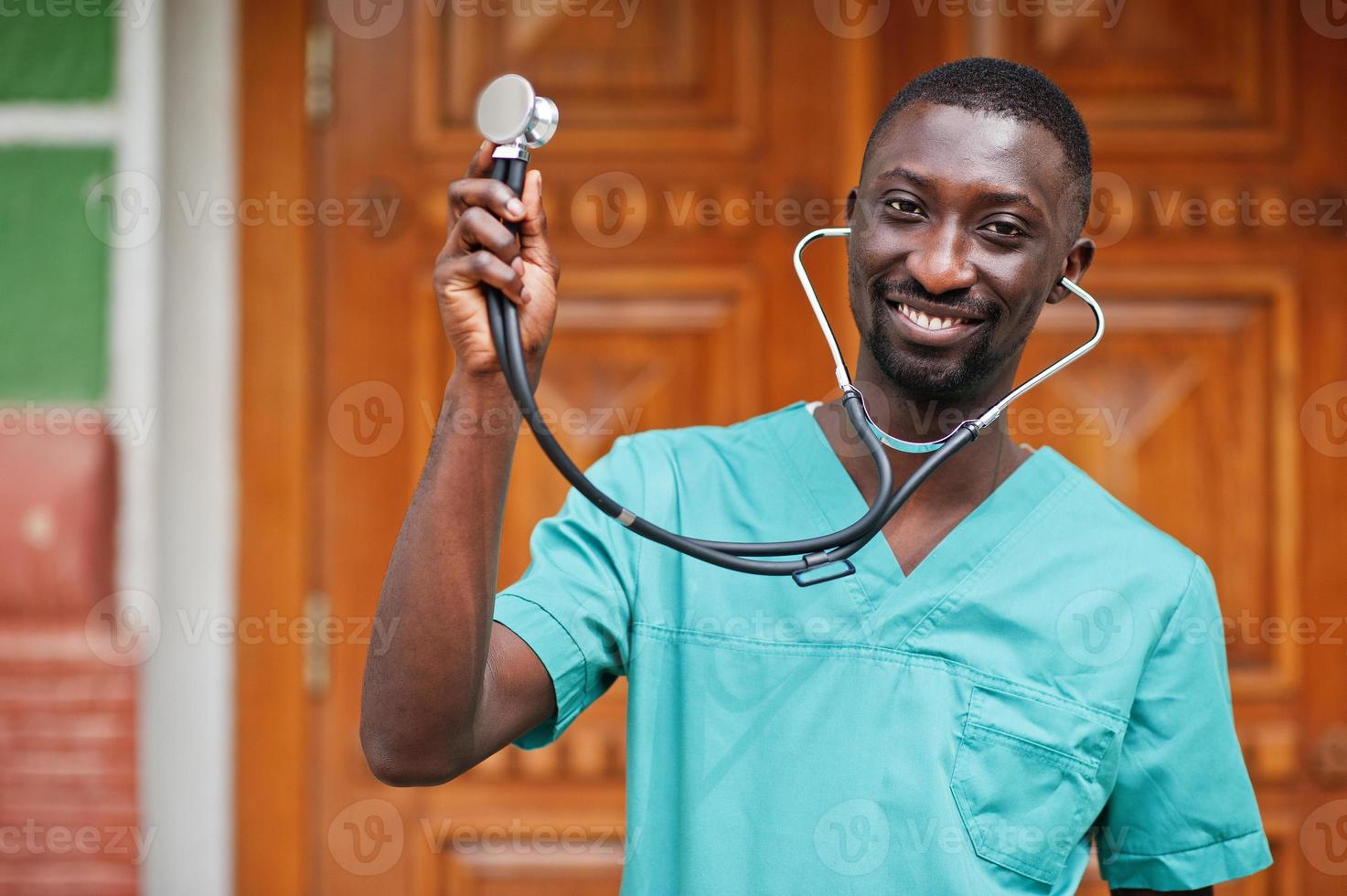 Portrait of African male doctor with stethoscope wearing green coat. photo