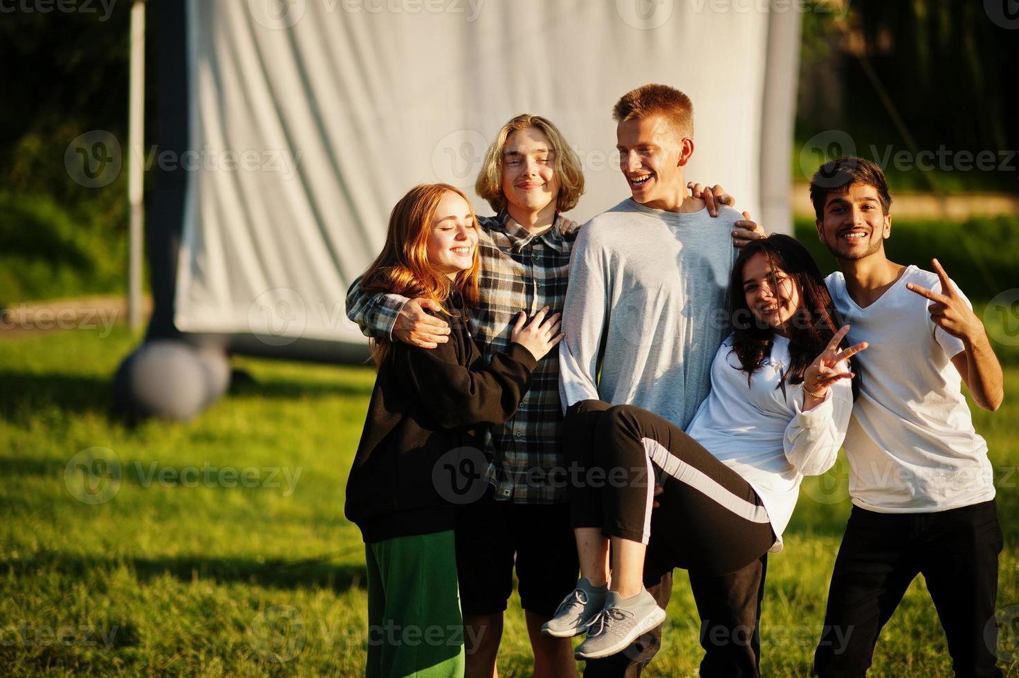 Young multi ethnic group of people watching movie at poof in open air cinema. photo