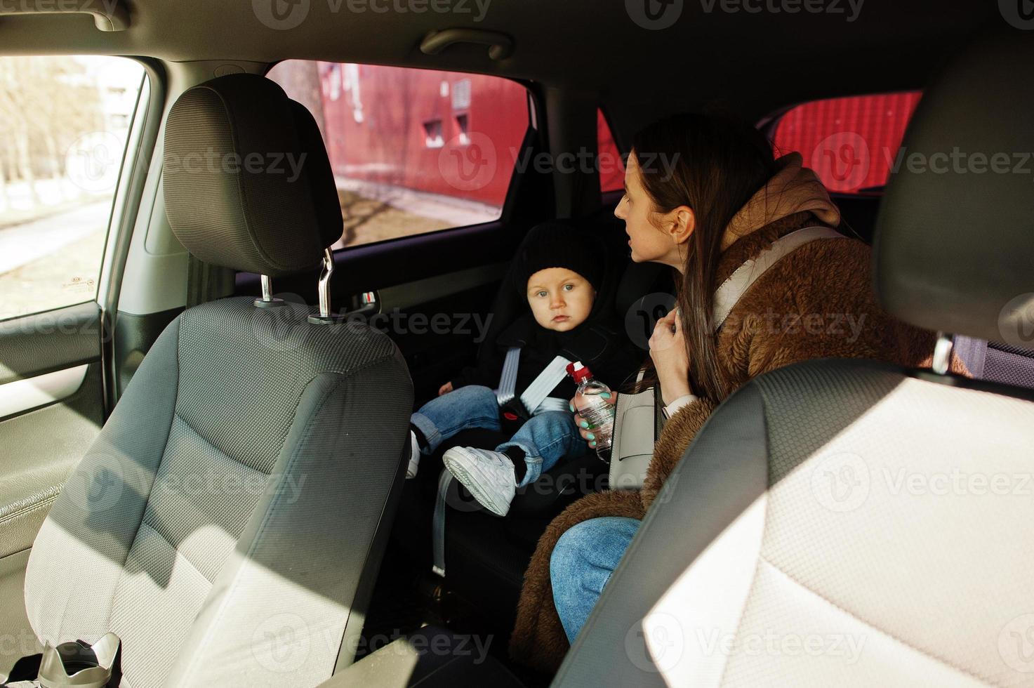 Young mother and child in car. Baby seat on chair. Safety driving concept. photo