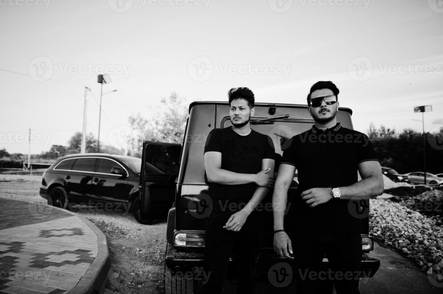 dos hermanos asiáticos se visten de negro y posan cerca de los autos todoterreno. foto