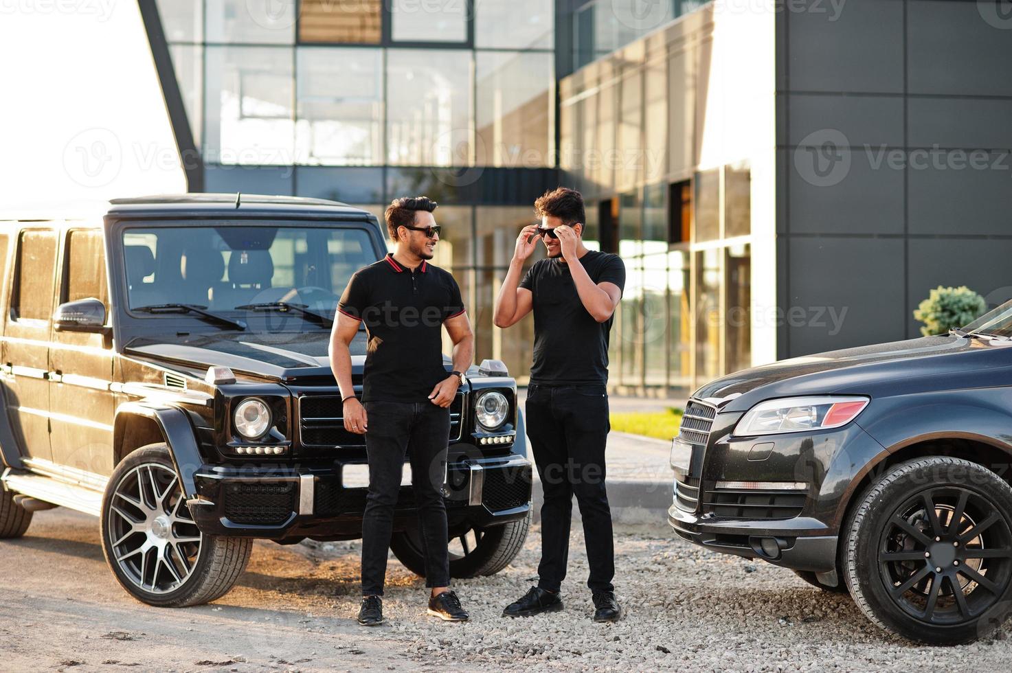 Two asian brothers man wear on all black posed near suv cars. photo
