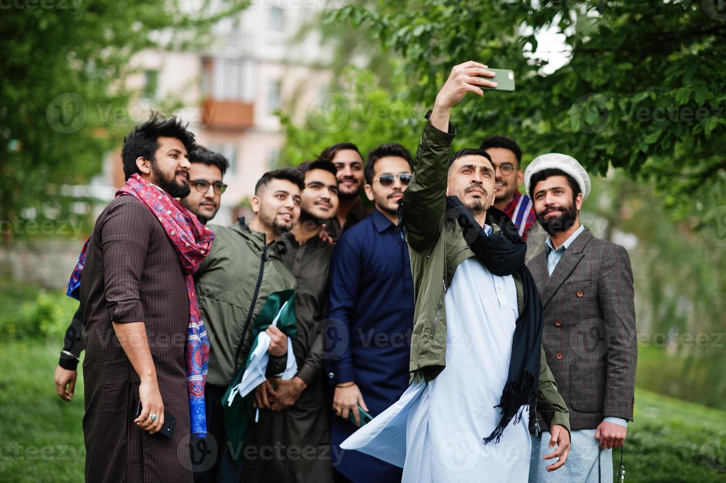 grupo de hombres paquistaníes vestidos con ropa tradicional salwar kameez o kurta haciendo selfie en el teléfono móvil. foto