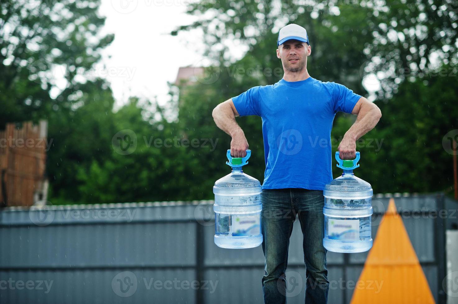 Delivery man with water bottles at hands. photo