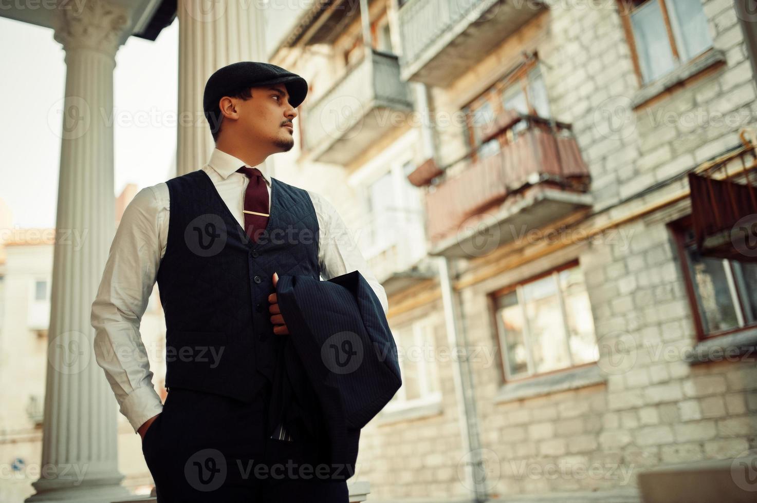 Portrait of retro 1920s english arabian business man wearing dark suit, tie and flat cap. photo