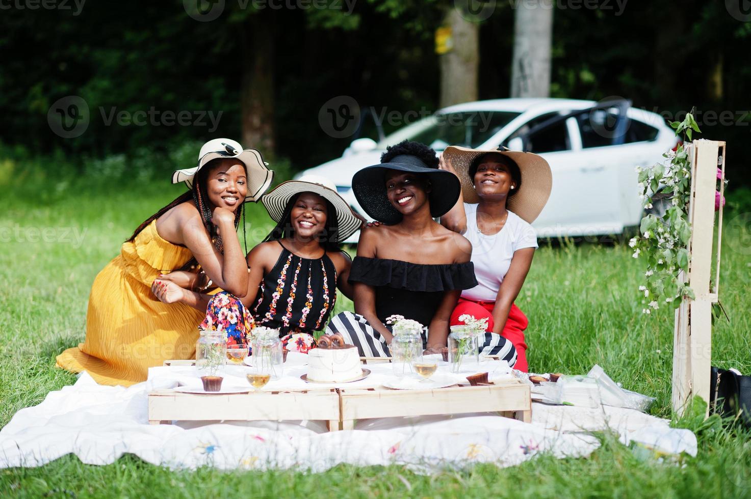 grupo de chicas afroamericanas celebrando la fiesta de cumpleaños y tintineando vasos al aire libre con decoración. foto
