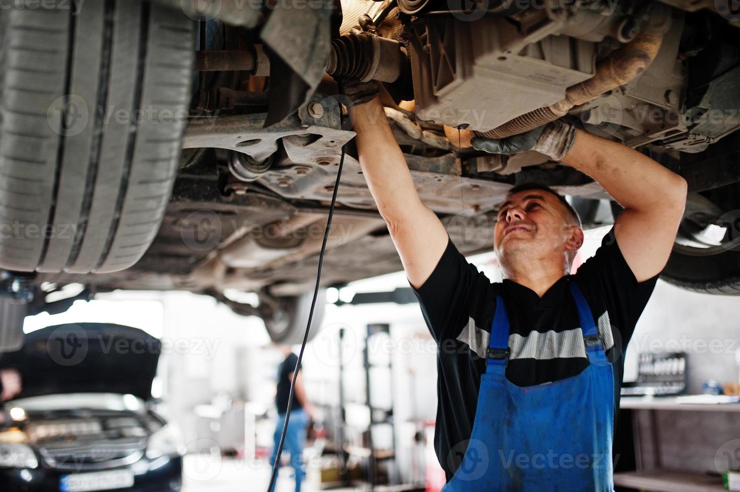 Car repair and maintenance theme. Mechanic in uniform working in auto service. photo