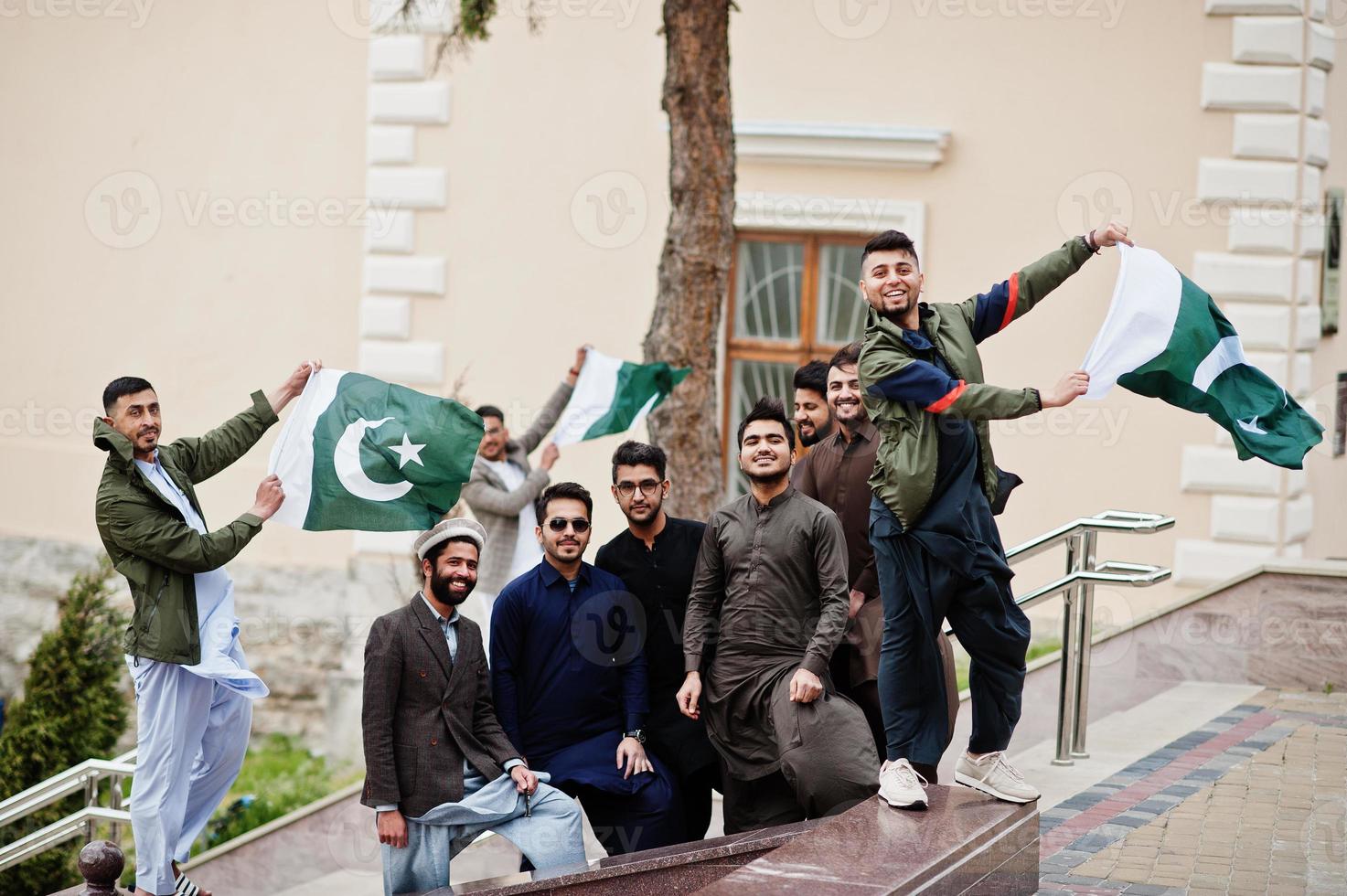 grupo de hombres paquistaníes vestidos con ropa tradicional salwar kameez o kurta con banderas de pakistán. foto