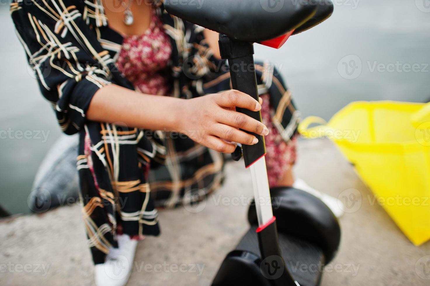 Beautiful african american woman sit near segway or hoverboard. Black girl with yellow cloth eco bags recycling symbol. photo