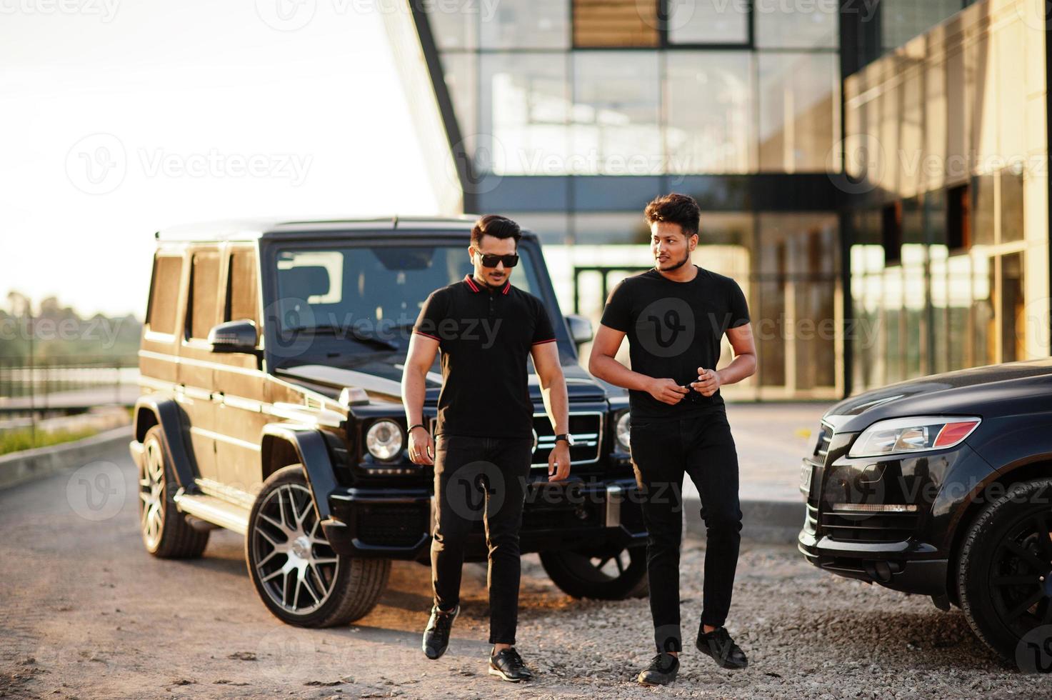 Two asian brothers man wear on all black posed near suv cars. photo