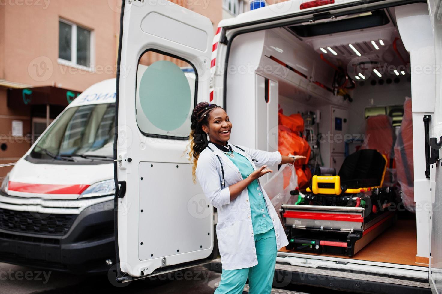 African american female paramedic standing in front of ambulance car. photo