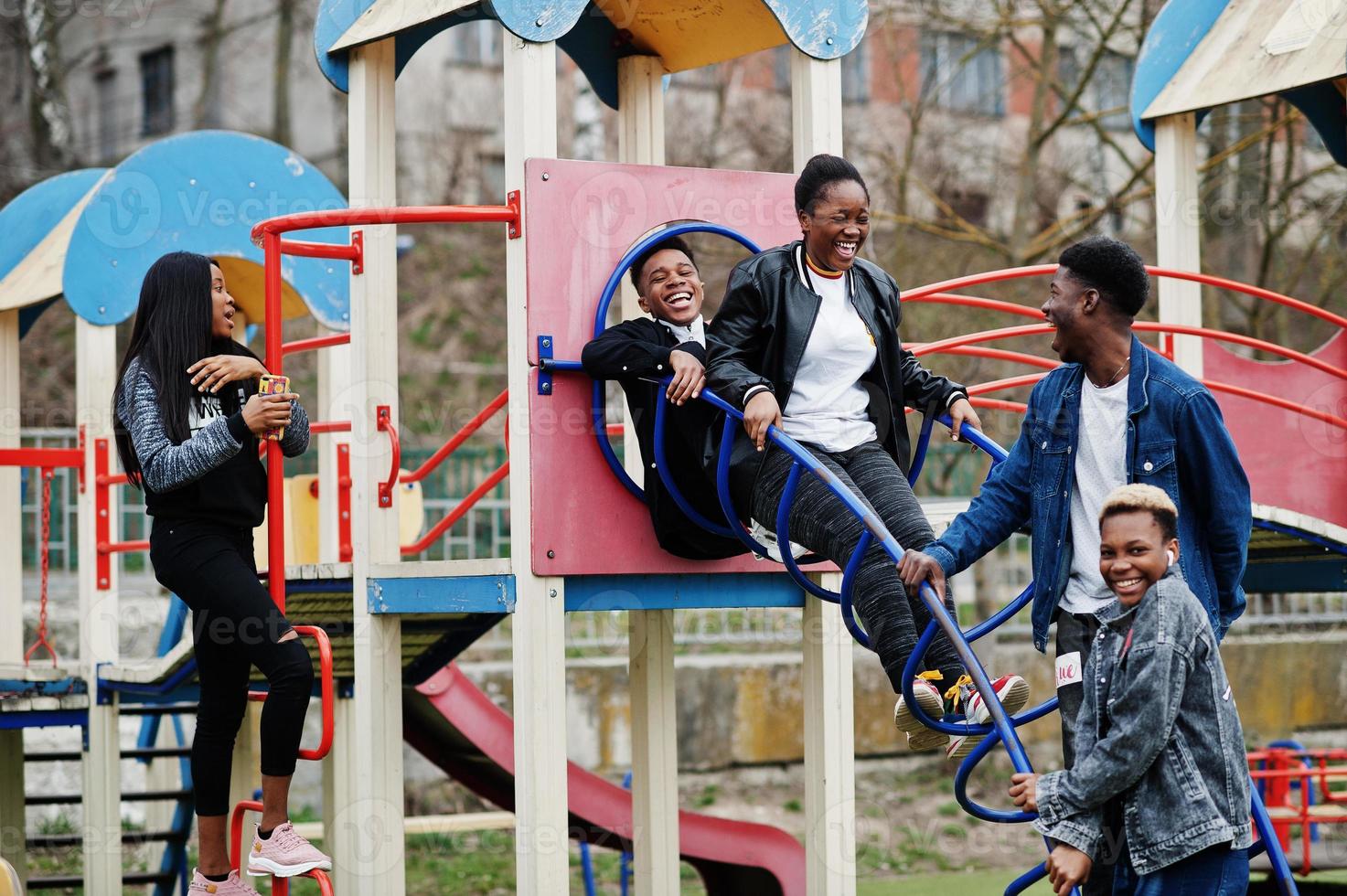 Young millennials african friends on playground, slide and swing. Happy black people having fun together. Generation Z friendship concept. photo