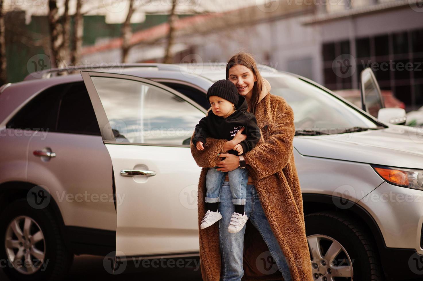 la joven madre y el niño se paran cerca de su auto todoterreno. concepto de conducción segura. foto