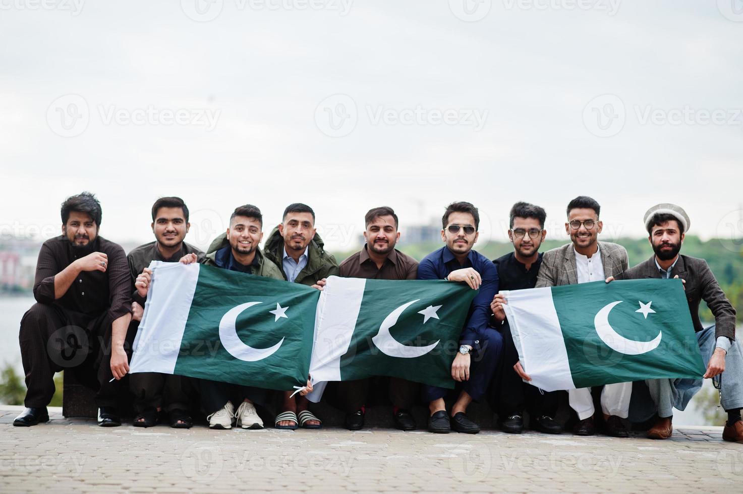 grupo de hombres paquistaníes vestidos con ropa tradicional salwar kameez o kurta con banderas de pakistán. foto