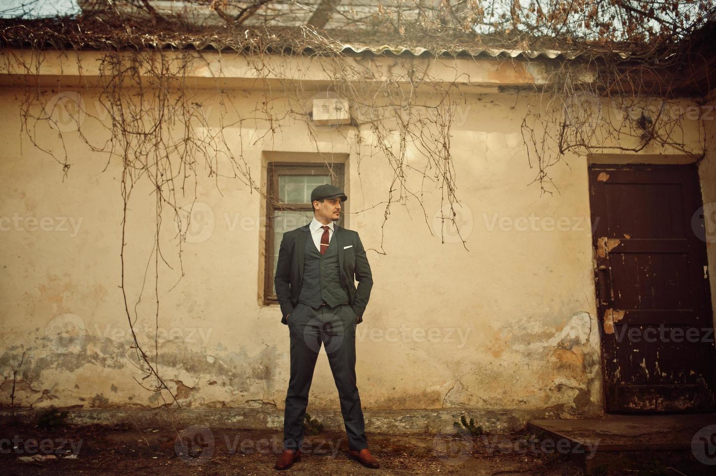 Portrait of retro 1920s english arabian business man wearing dark suit, tie and flat cap. photo