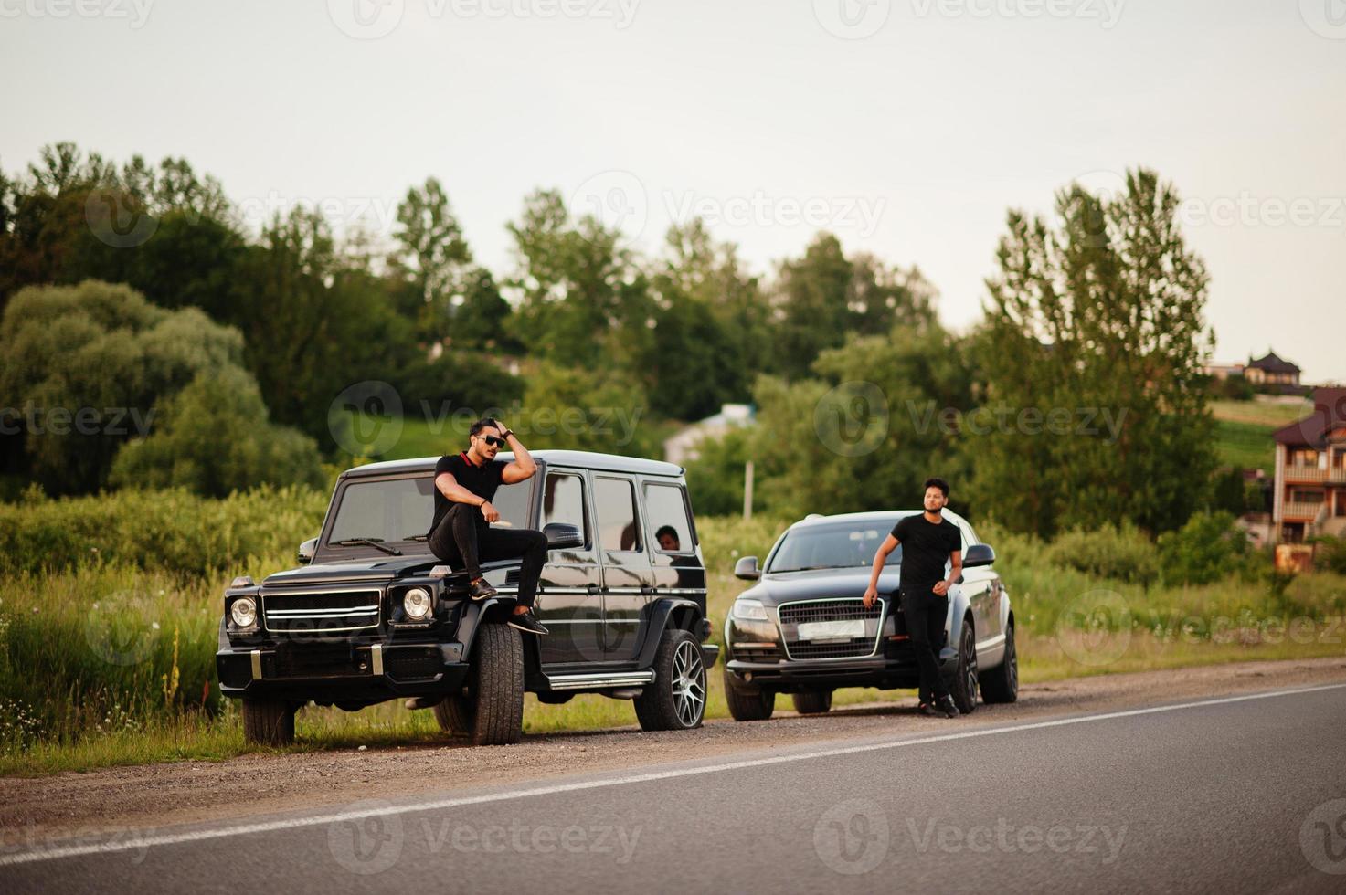 Two asian brothers man wear on all black posed near suv cars. photo