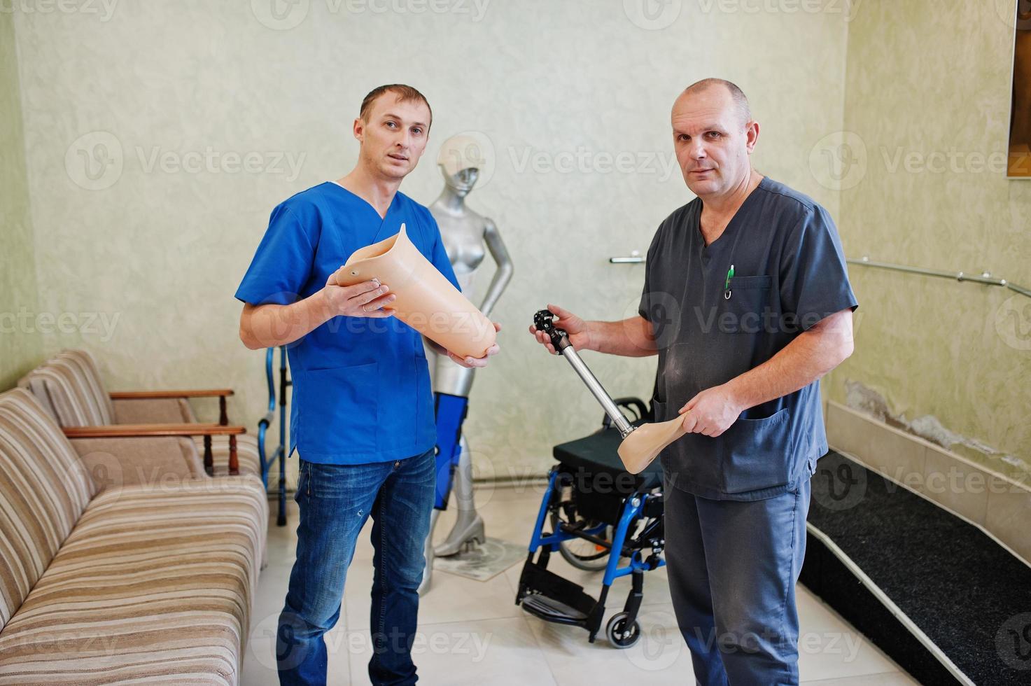 Two prosthetist man workers with prosthetic leg working in laboratory. photo