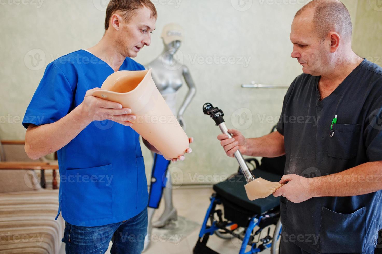 Two prosthetist man workers with prosthetic leg working in laboratory. photo