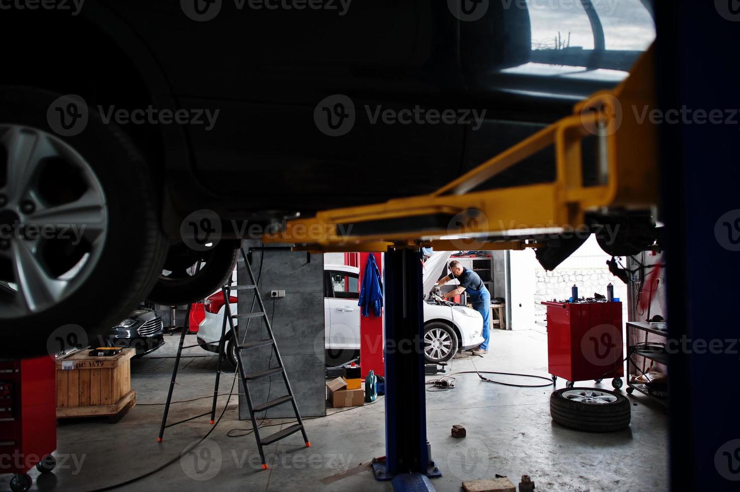 Car repair and maintenance theme. Mechanic in uniform working in auto service. photo