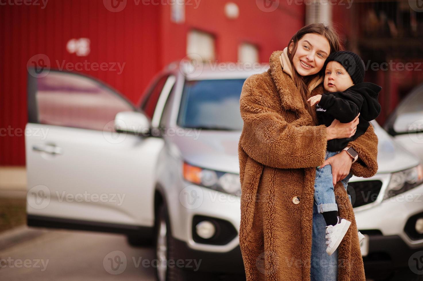 la joven madre y el niño se paran cerca de su auto todoterreno. concepto de conducción segura. foto