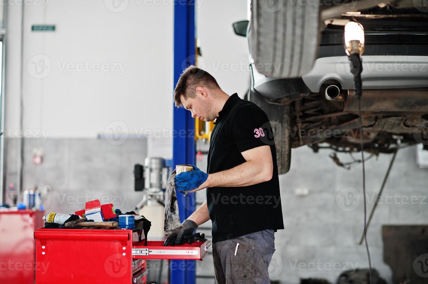 Car repair and maintenance theme. Mechanic in uniform working in auto service. photo