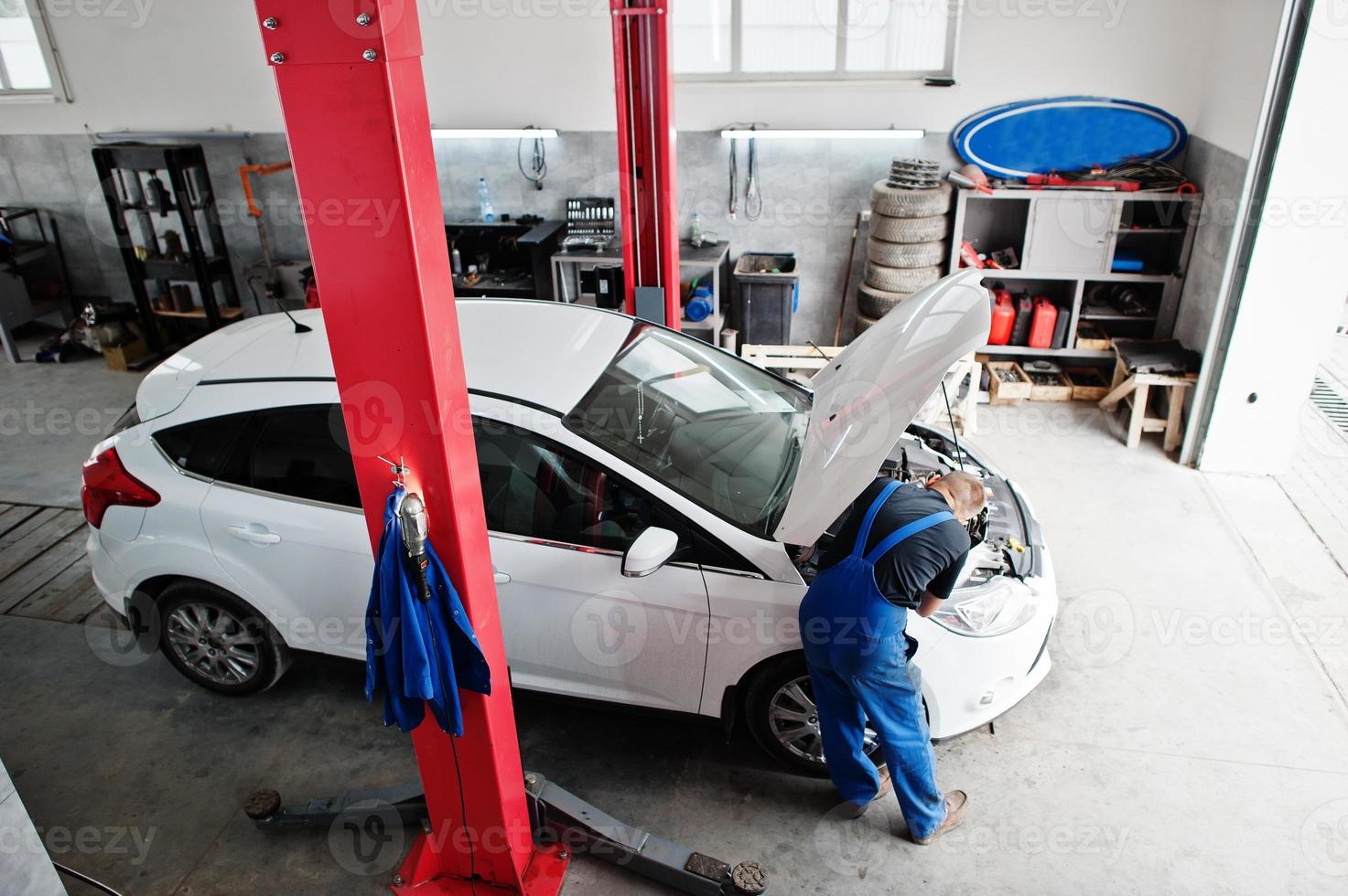 Car repair and maintenance theme. Mechanic in uniform working in auto service. photo