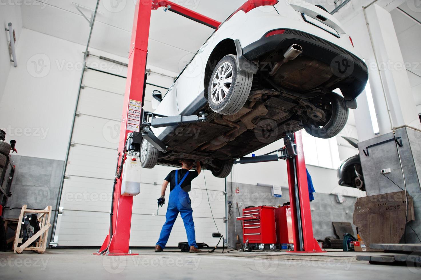 Car repair and maintenance theme. Mechanic in uniform working in auto service. photo