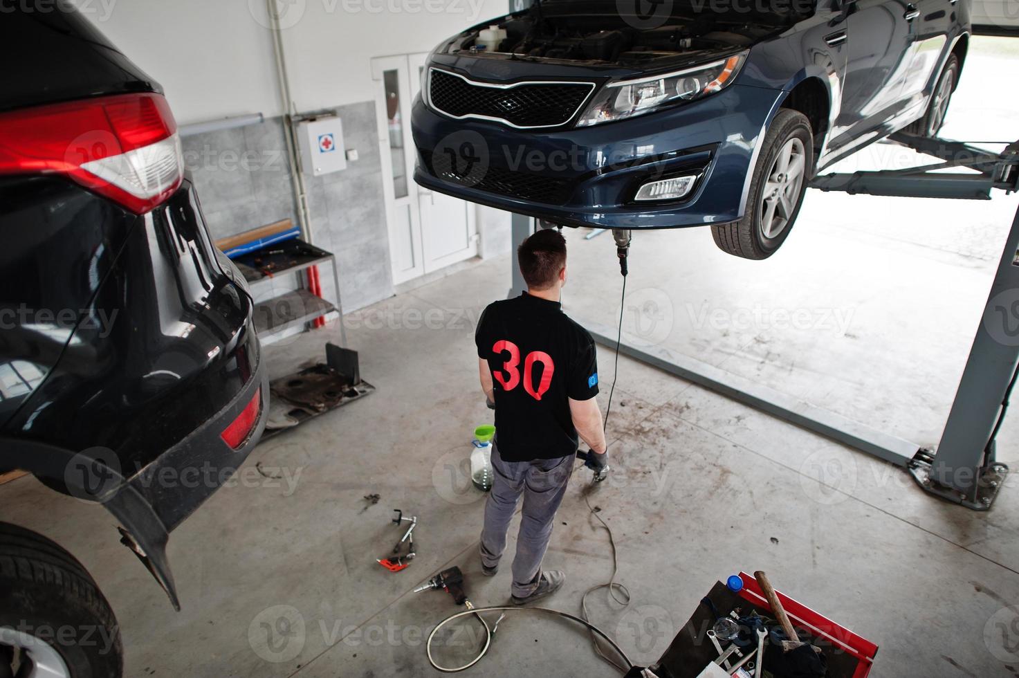 Car repair and maintenance theme. Mechanic in uniform working in auto service. photo