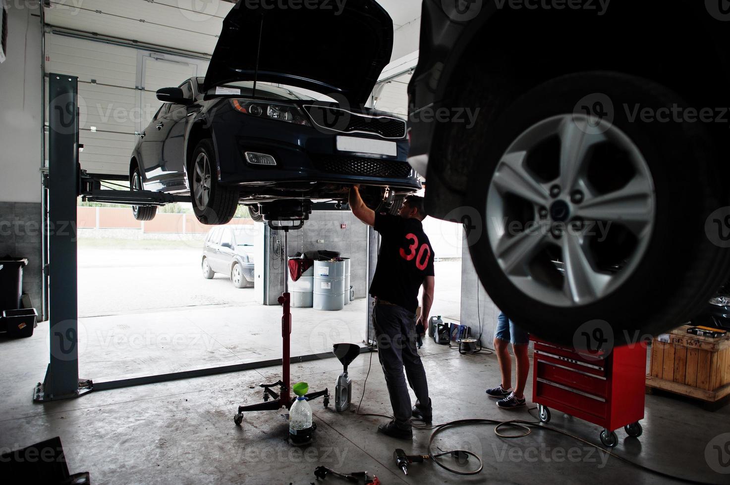 Car repair and maintenance theme. Mechanic in uniform working in auto service. photo