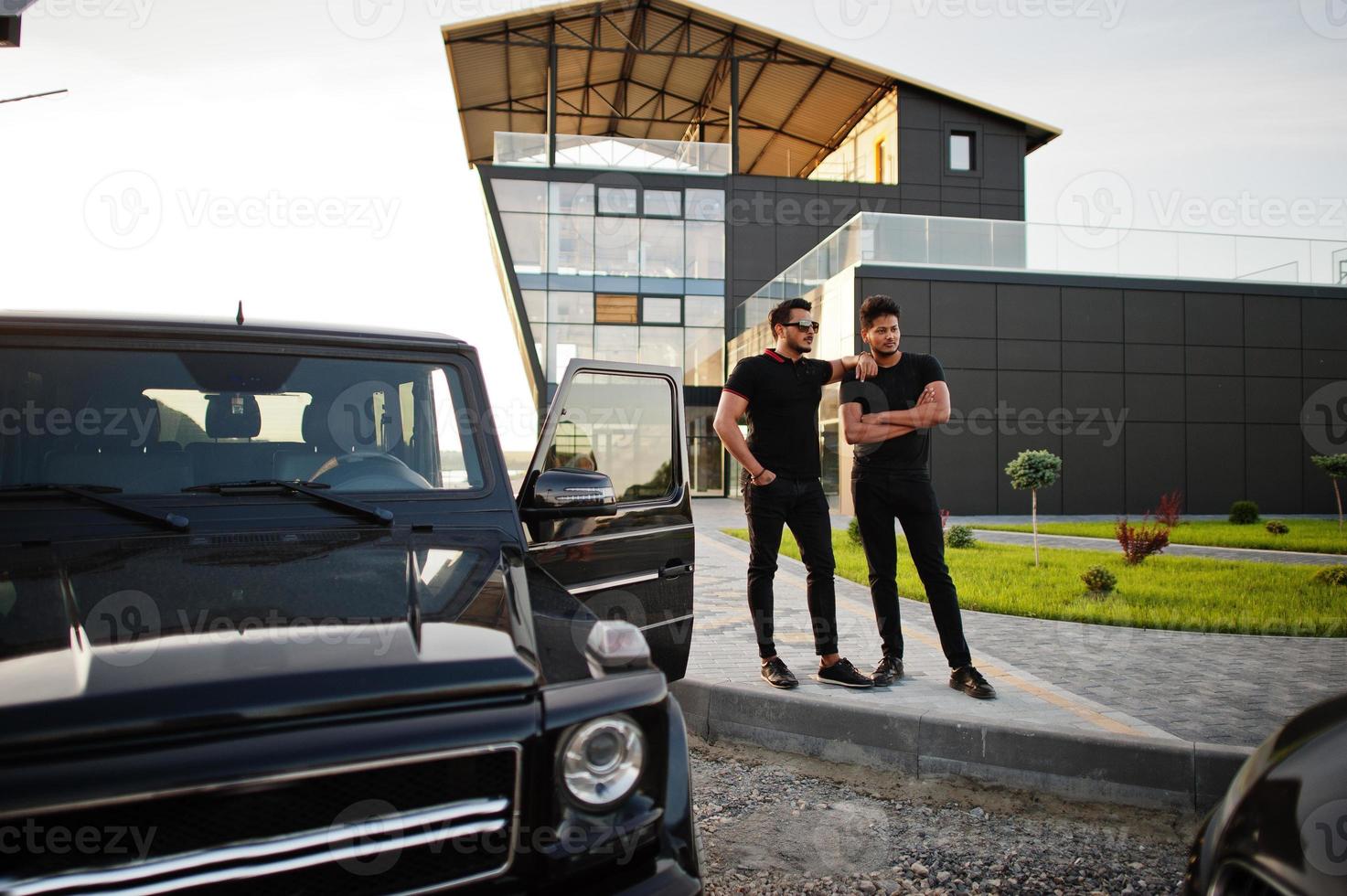 Two asian brothers man wear on all black posed near suv cars. photo