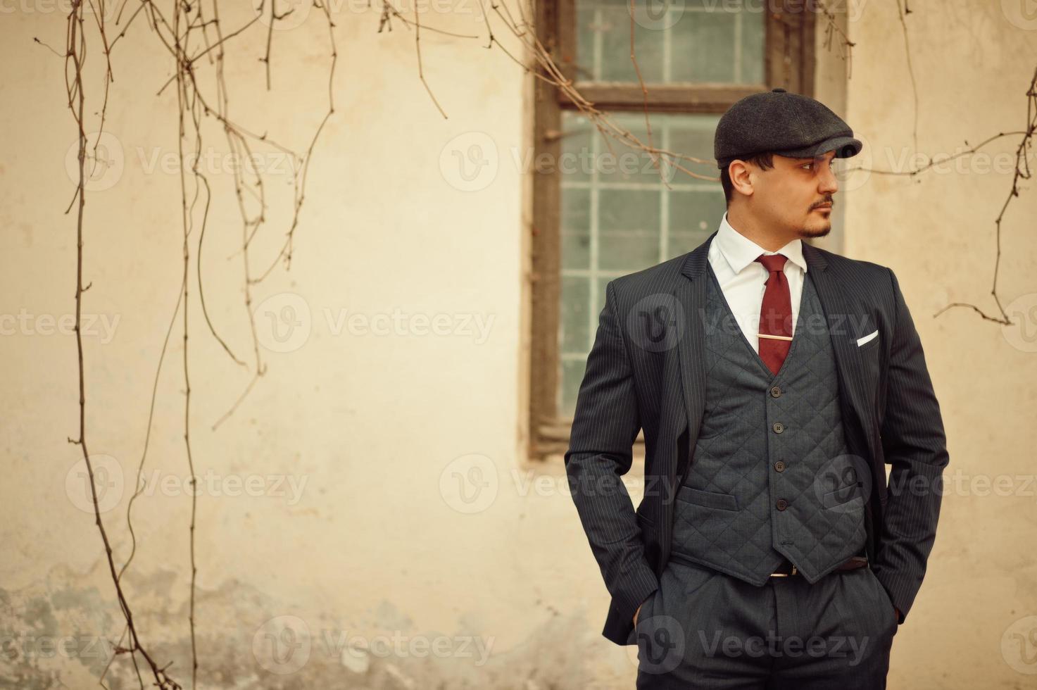 Portrait of retro 1920s english arabian business man wearing dark suit, tie and flat cap. photo