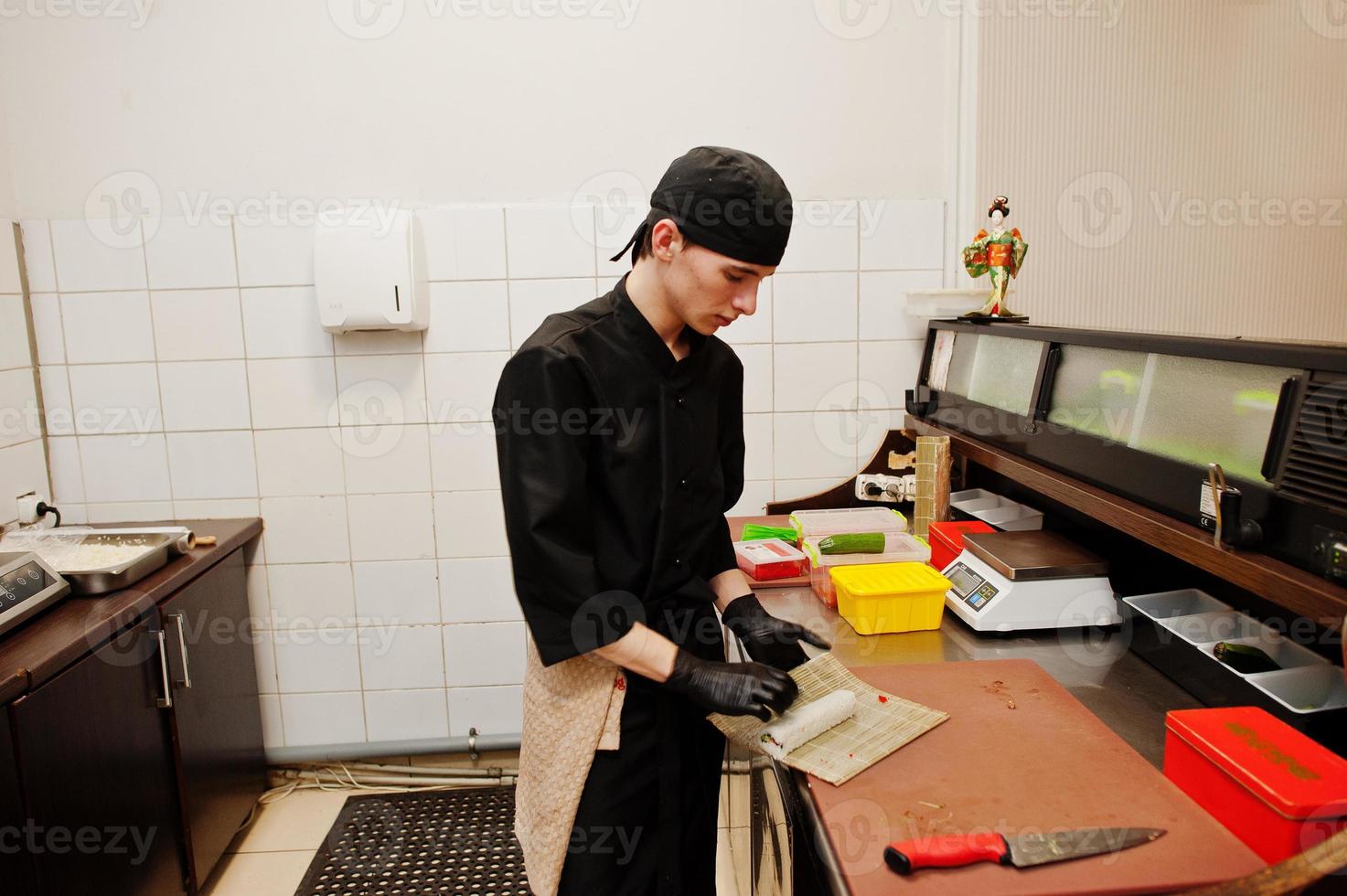 Professional chef wear in black making sushi and rolls in a restaurant kitchen of japanese traditional food. photo