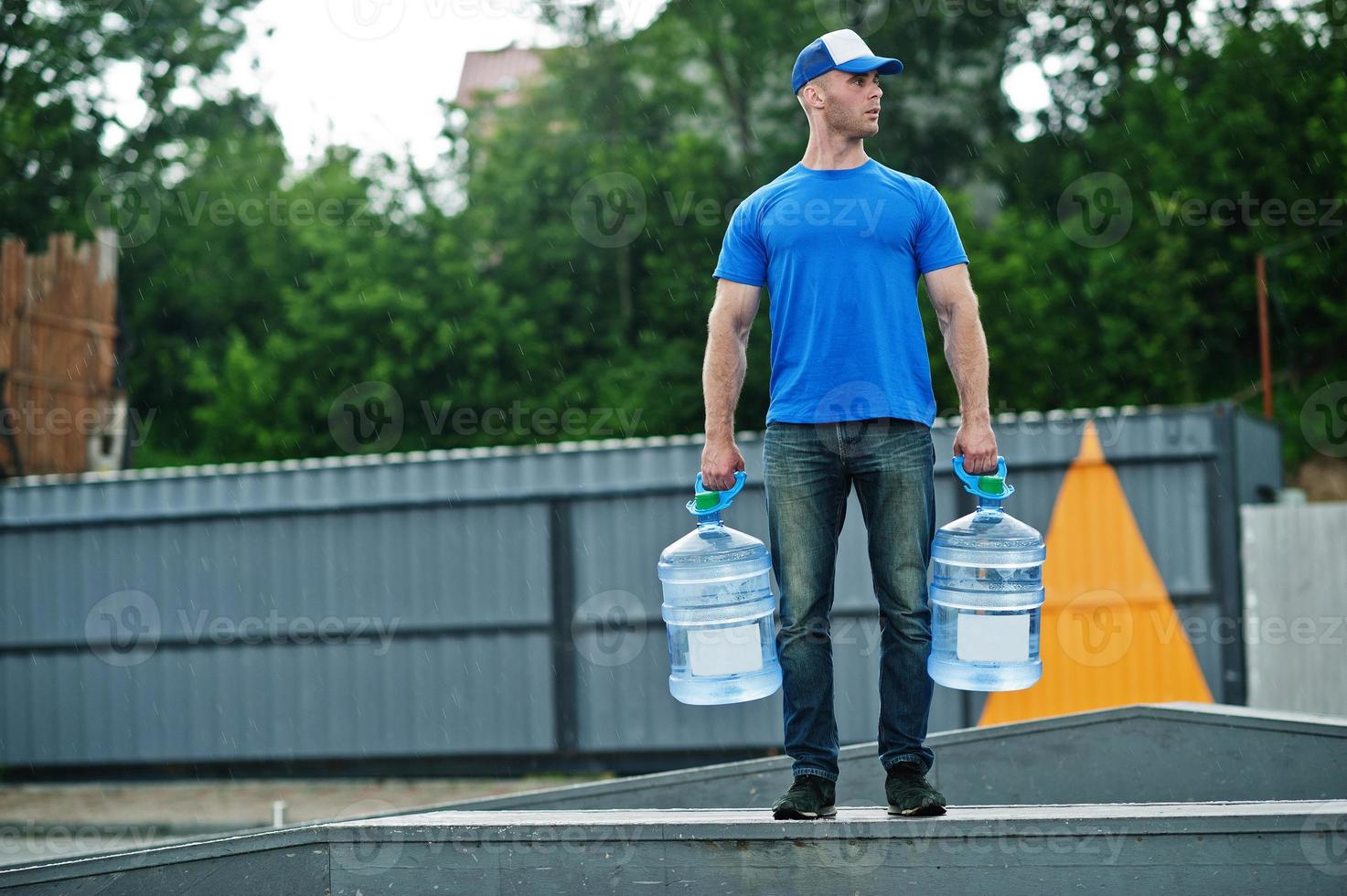Delivery man with water bottles at hands. photo