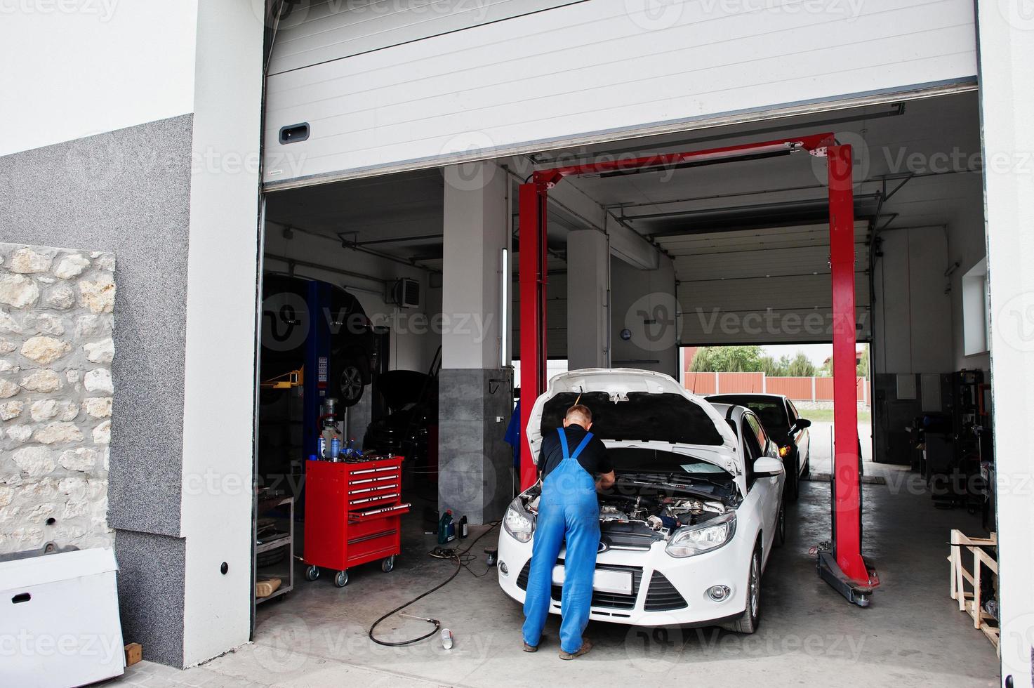 Car repair and maintenance theme. Mechanic in uniform working in auto service. photo