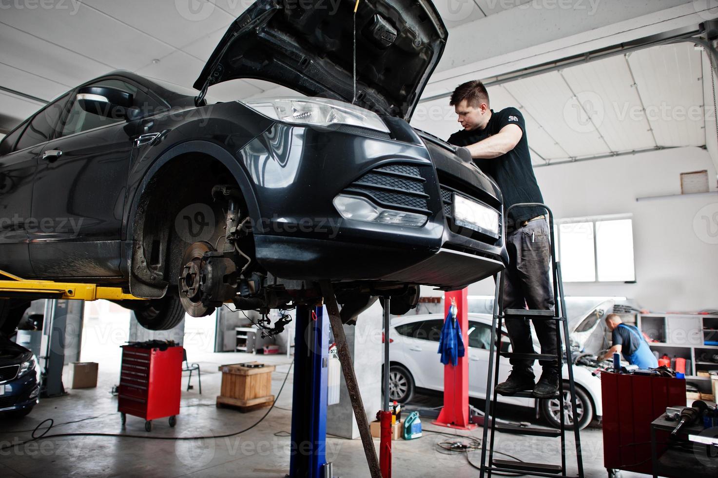 Car repair and maintenance theme. Mechanic in uniform working in auto service. photo