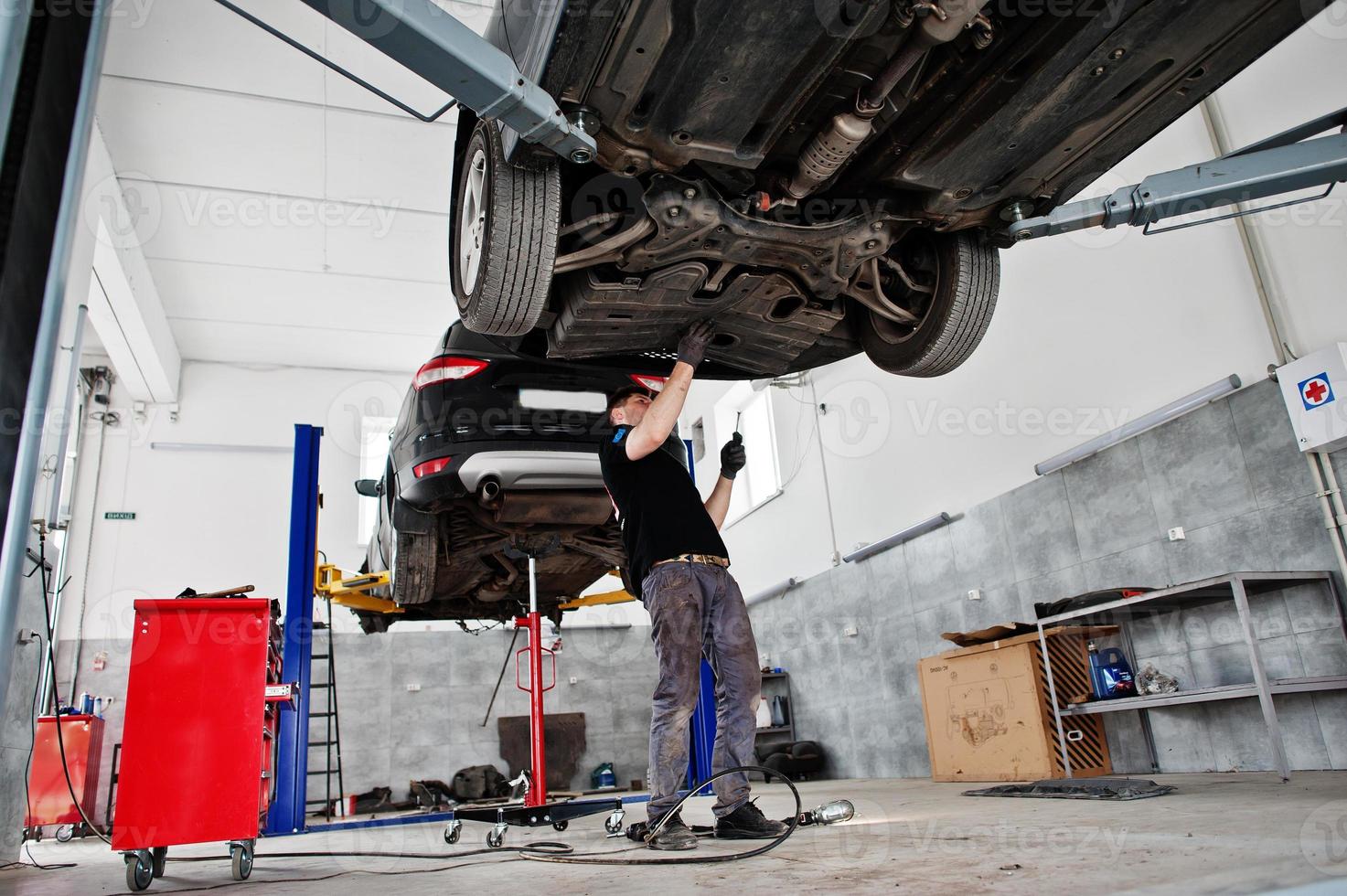 Car repair and maintenance theme. Mechanic in uniform working in auto service. photo