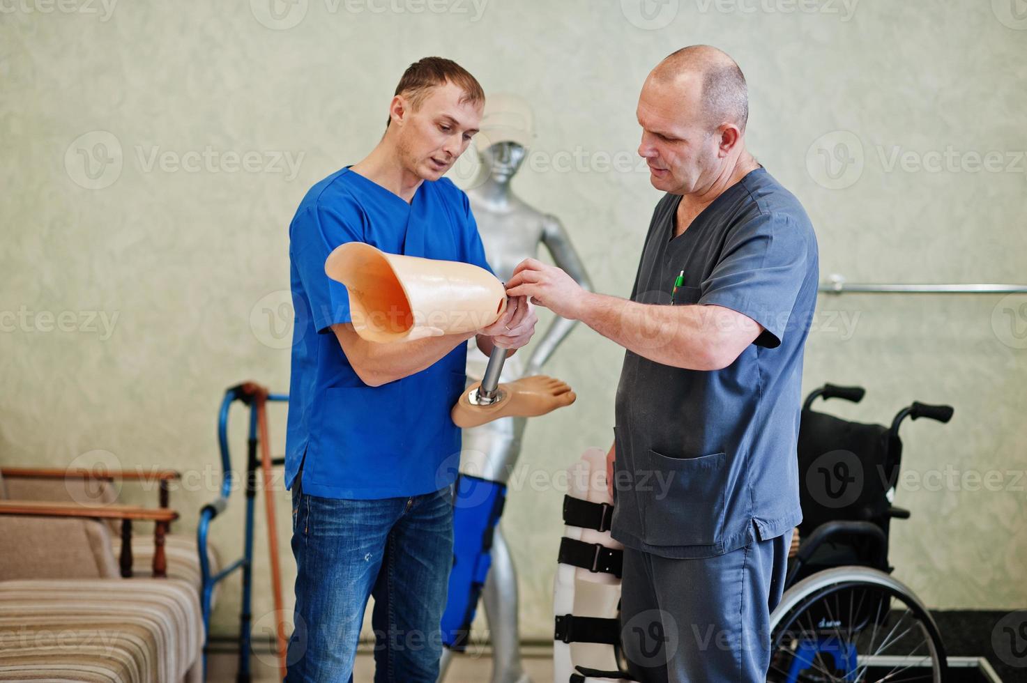 Two prosthetist man workers with prosthetic leg working in laboratory. photo