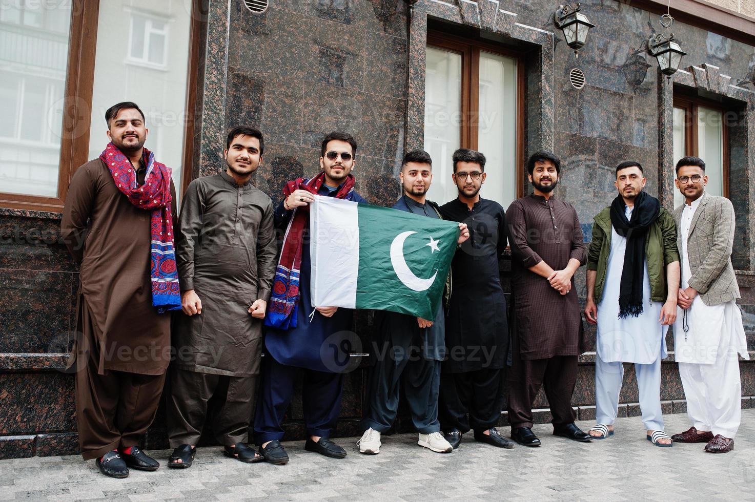 grupo de hombres paquistaníes vestidos con ropa tradicional salwar kameez o kurta con banderas de pakistán. foto