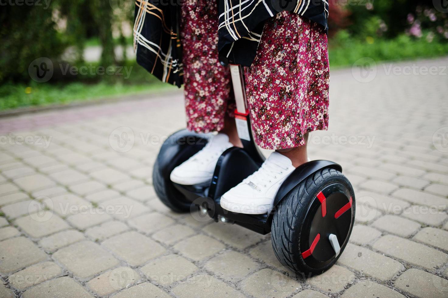 Close up legs of african american woman using segway or hoverboard. Black girl on dual wheel self balancing electrical scooter. photo